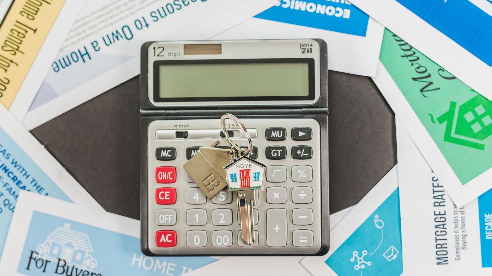 Calculator, house keys and real estate documents on a desk