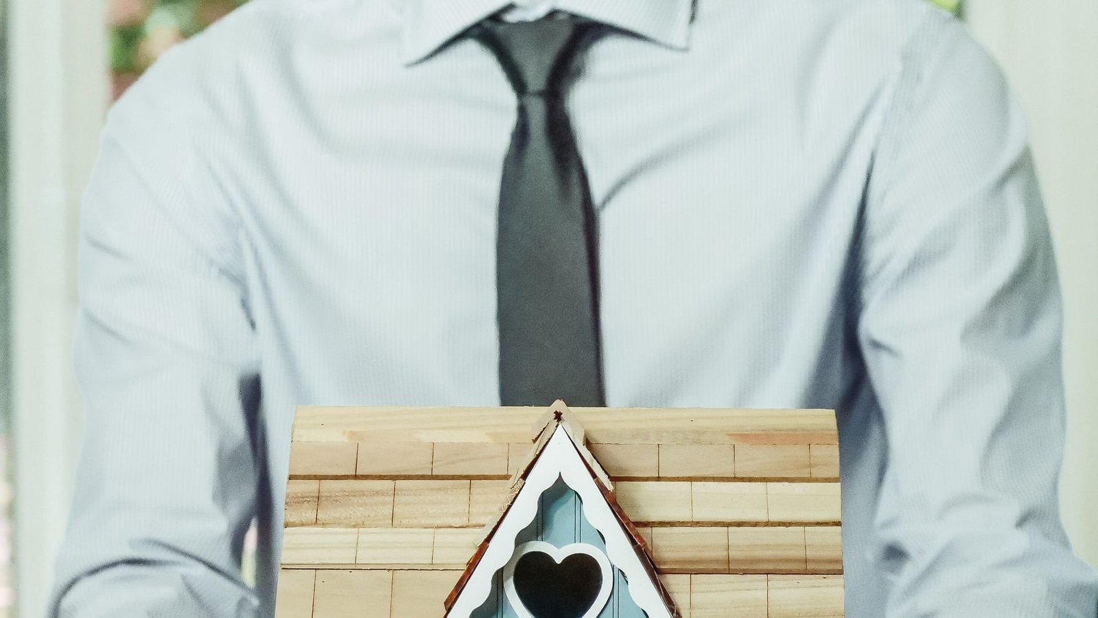 Smiling mortgage professional holding a small model house