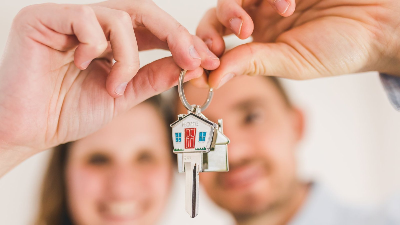 Smiling couple holding a house-shaped key